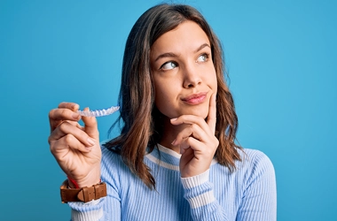 Orthodontist Ellicott City MD Girl With Aligners A girl holding clear aligners. She is in a blue shirt.