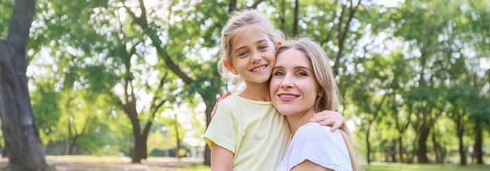 A mother and daughter smiling outside.
