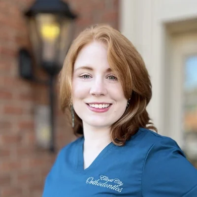 Meghan smiling in front of a brick wall.